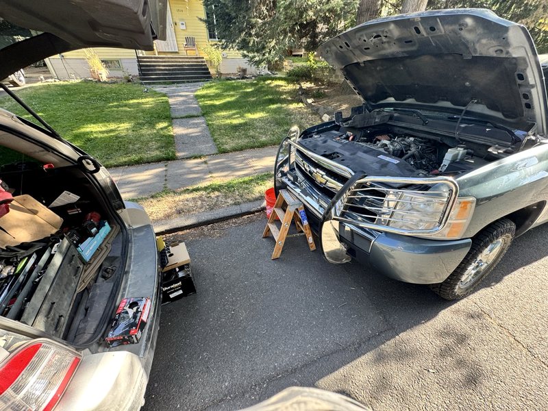 Farrell's Automotive mobile service vehicle parked curbside next to a Chevy Silverado with the hood open during an overheating repair