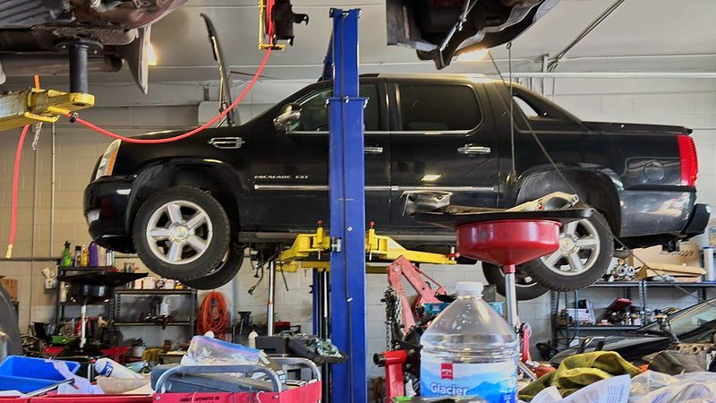 Black Cadillac Escalade EXT up on a lift for repair