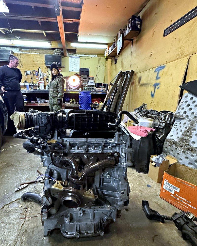 Replacement engine on the floor of a customer's small home garage during a winter motor swap by Farrell's Automotive